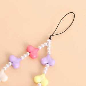 Detail of sweet macaron heart beads and imitation pearls on a mobile phone strap
