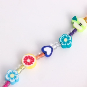 Détail d'une chaîne de téléphone artisanale avec fleurs colorées et perles de fruits
