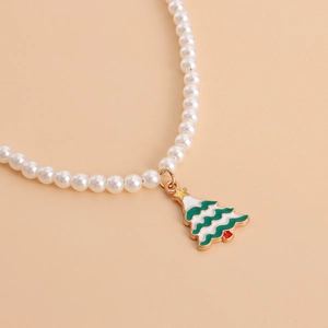 Close-up of pearl necklace featuring a green and white Christmas tree pendant with gold trim