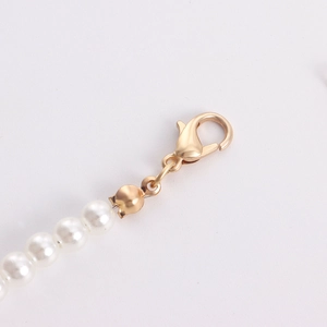 Detail of gold lobster clasp connected to elegant white pearl necklace strand