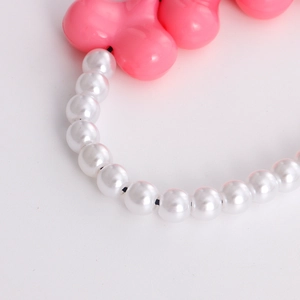Detailed macro view of white acrylic pearls and pink geometric heart charm phone lanyard