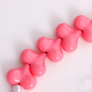 Detailed view of pink heart-shaped acrylic beads and white faux pearl on phone strap