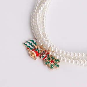 Detailed macro view of triple-layer pearl necklace with festive Christmas charms