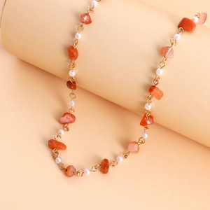 Détails des pierres orange et des petites perles blanches sur collier plaqué or