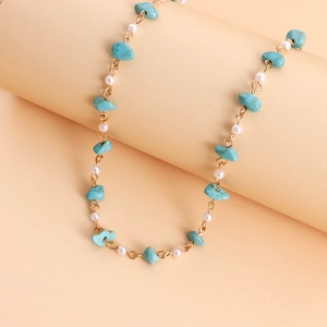 Vue détaillée des pierres turquoises et perles blanches sur le collier doré fini
