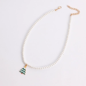 Detailed macro view of faux pearl necklace with green enamel Christmas tree charm