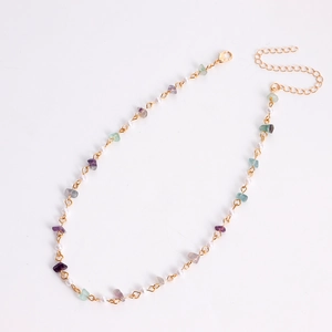 Détail du collier de perles avec fermoir mousqueton doré, perles blanches et pierres colorées