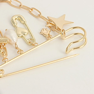Detailed close-up of golden brooch with star charm and white baroque pearl pendant