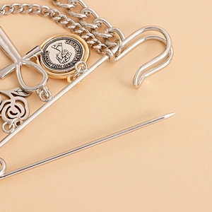 Detailed macro view of punk style rose brooch with silver cross and vintage coin charm