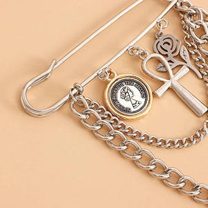Detailed view of silver safety pin brooch with punk chains, coin and rose pendants