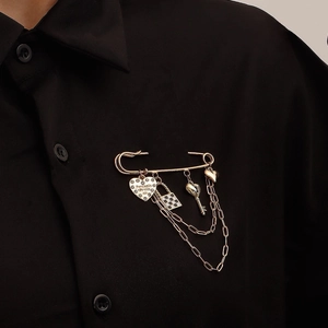Golden safety pin brooch featuring checkered lock, key, and heart charms with double chains