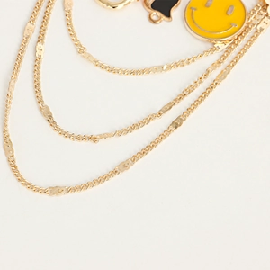 Gros plan sur collier doré multicouche avec pendentifs smiley jaune et cœur noir