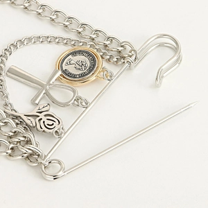 Close-up of a punk-style rose brooch with chain tassels and gold queen coin pendants