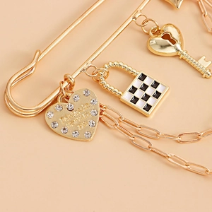 Detailed close-up of gold safety pin brooch with checkered lock and heart key charms