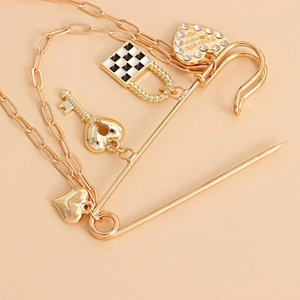 Detail of golden heart and checkerboard pendants hanging from a large safety pin brooch