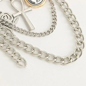 Macro view of multi-layer punk necklace featuring Ankh cross, rose, and Queen coin charms