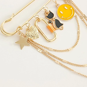 Détail macro d'une broche épingle dorée avec pendentifs smiley jaune et chat noir