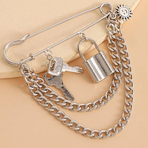 Detailed view of silver punk safety pin brooch with hanging chains, padlock, and key charms