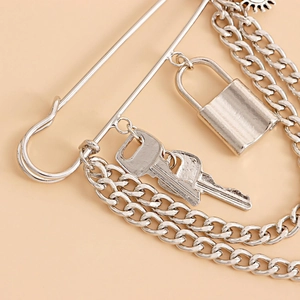 Detail of punk style silver brooch with safety pin, layered chains, lock and key pendants
