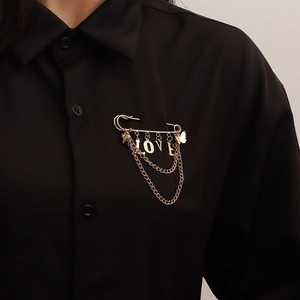 Gold LOVE letter brooch with heart and butterfly charms on black fabric background