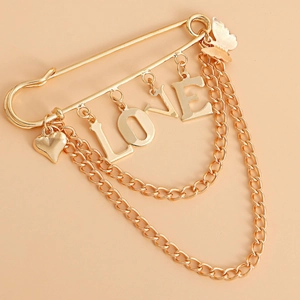 Detail of gold LOVE heart brooch pin with layered metal chains and butterfly charms