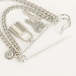 Detail of silver punk style brooch with padlock, keys, safety pin and sun pendants