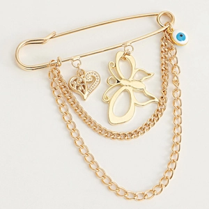 Détail d'une broche dorée avec breloques cœur ajouré, papillon et perle d'œil maléfique