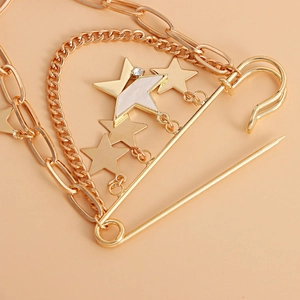 Détail de la broche punk dorée avec pendentifs étoiles et chaînes en métal superposées