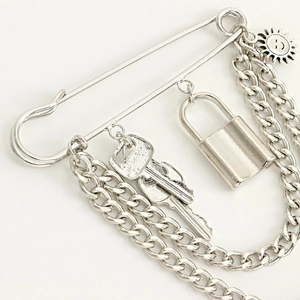Detail view of punk style silver brooch with padlock, keys, and layered chains