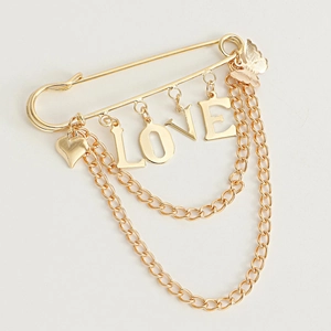 Detail of golden LOVE heart brooch with butterfly charms and hanging double tassels