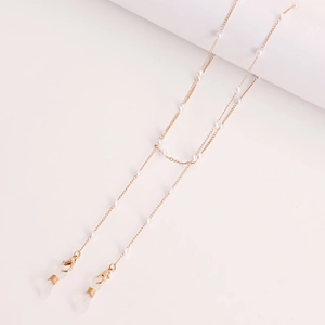 Detail of golden eyeglass chain featuring delicate pearls and lobster clasps