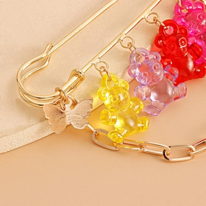 Detail einer goldenen Sicherheitsnadel-Brosche mit Harzbären und Schmetterling