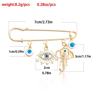 Golden geometric evil eye safety pin brooch with elephant charm and crystal detail 7cm