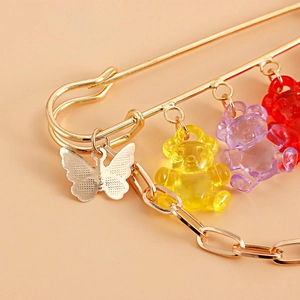 Makroaufnahme der goldenen Sicherheitsnadel-Brosche mit Harz-Gummibärchen und Schmetterling