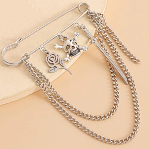 Close-up of gothic silver brooch featuring skull, rose, sword charms and metal chains
