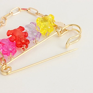 Detailansicht der bunten Harzbären an einer goldenen Sicherheitsnadel Brosche mit Kette