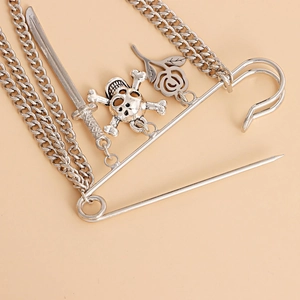 Close-up of gothic silver brooch with chain tassels, skull, sword, and rose charms