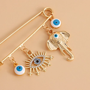 Detailed close-up of golden safety pin brooch with elephant and evil eye charms