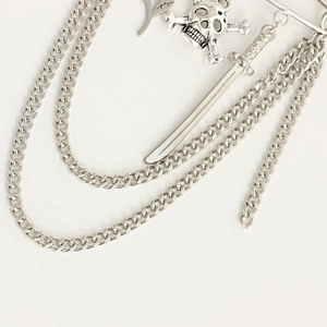 Detailed macro view of silver punk brooch with multi-layer chains, skull and sword charms