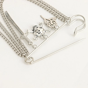 Macro view of vintage silver skull brooch with long tassels and katana pendant