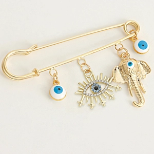 Detail of gold safety pin brooch with blue evil eye charms and elephant pendant