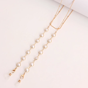 Detail of gold metal eyewear chain featuring white beads and silicone anti-slip loops