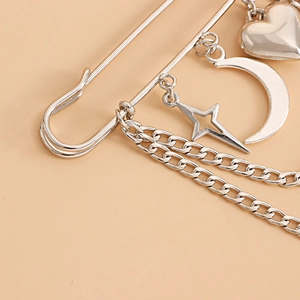 Detail of silver safety pin brooch with heart, moon, star pendants and metal chains