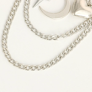 Detail of silver layered chain with heart, moon, and star charms on white backdrop