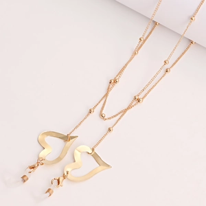 Détail de la chaîne à lunettes dorée montrant des pendentifs cœur et des fermoirs mousqueton