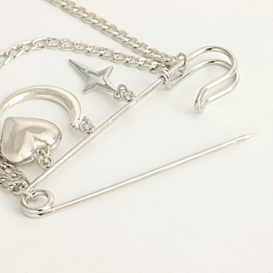 Macro view of silver punk safety pin brooch with heart moon and star charms