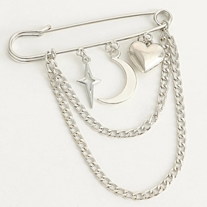 Detail of silver heart crescent moon and star charms on a metal pin brooch with chains