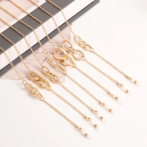 Macro detail of various gold metal eyewear chains with decorative links and silicone loops