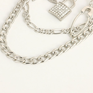 Close-up of punk silver layered chain with rhinestone padlock and paperclip charms