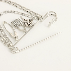 Detail of punk silver safety pin brooch with rose, padlock charms and multi-layer chains